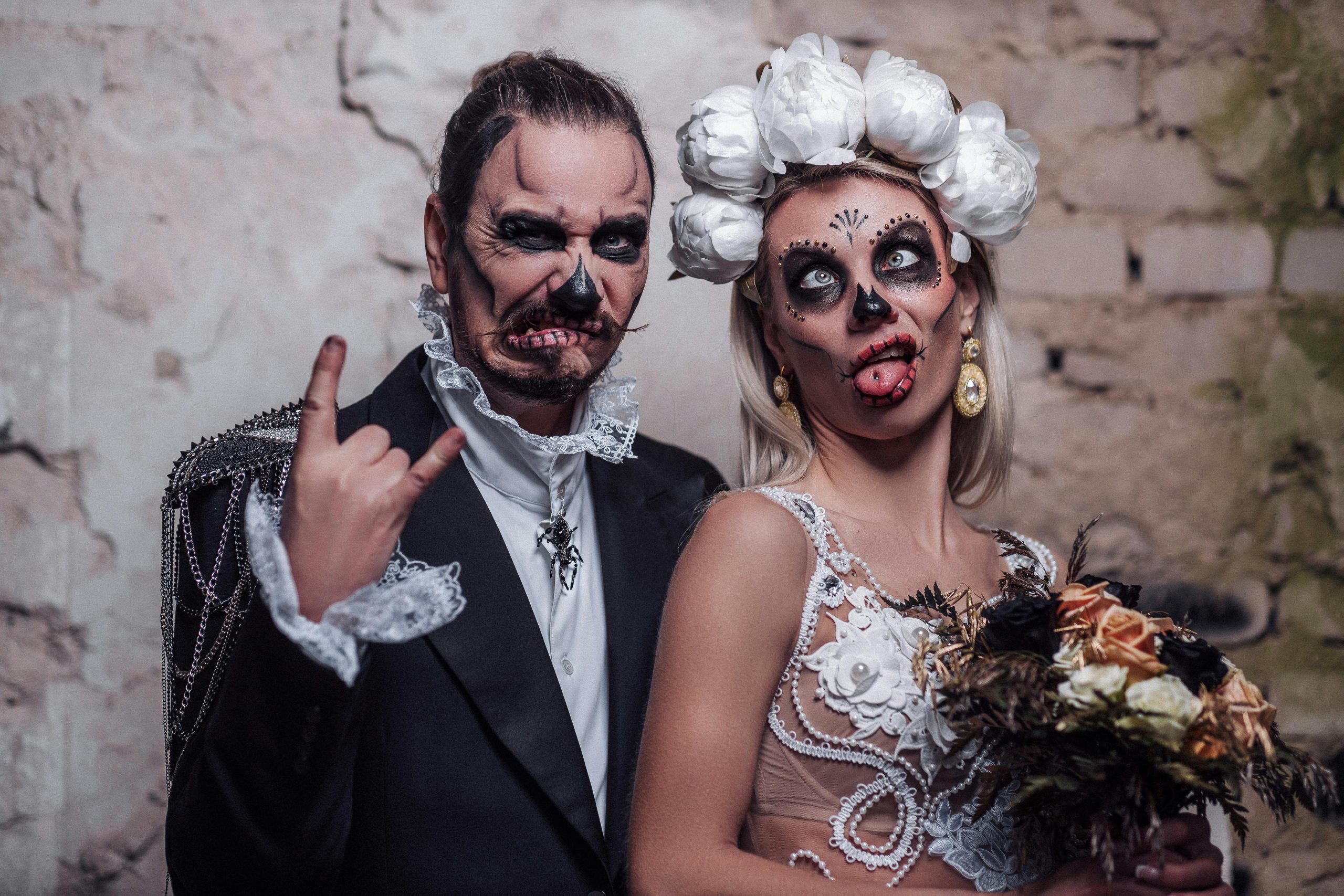 Couple dressed in Halloween-themed wedding attire with skeleton makeup, creating a gothic and festive atmosphere.