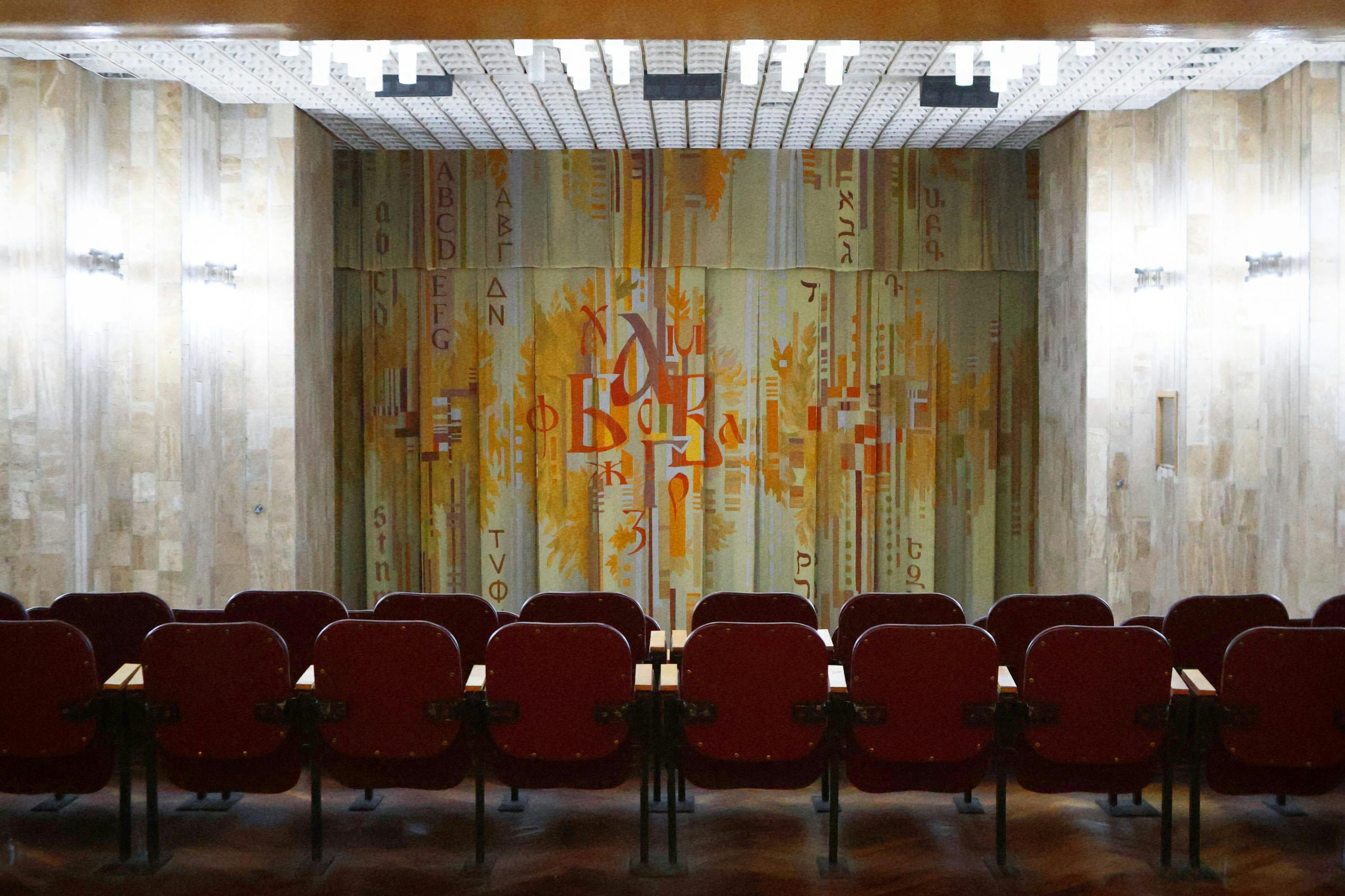 Empty theater hall with vintage decor and abstract art curtain, creating a nostalgic atmosphere.