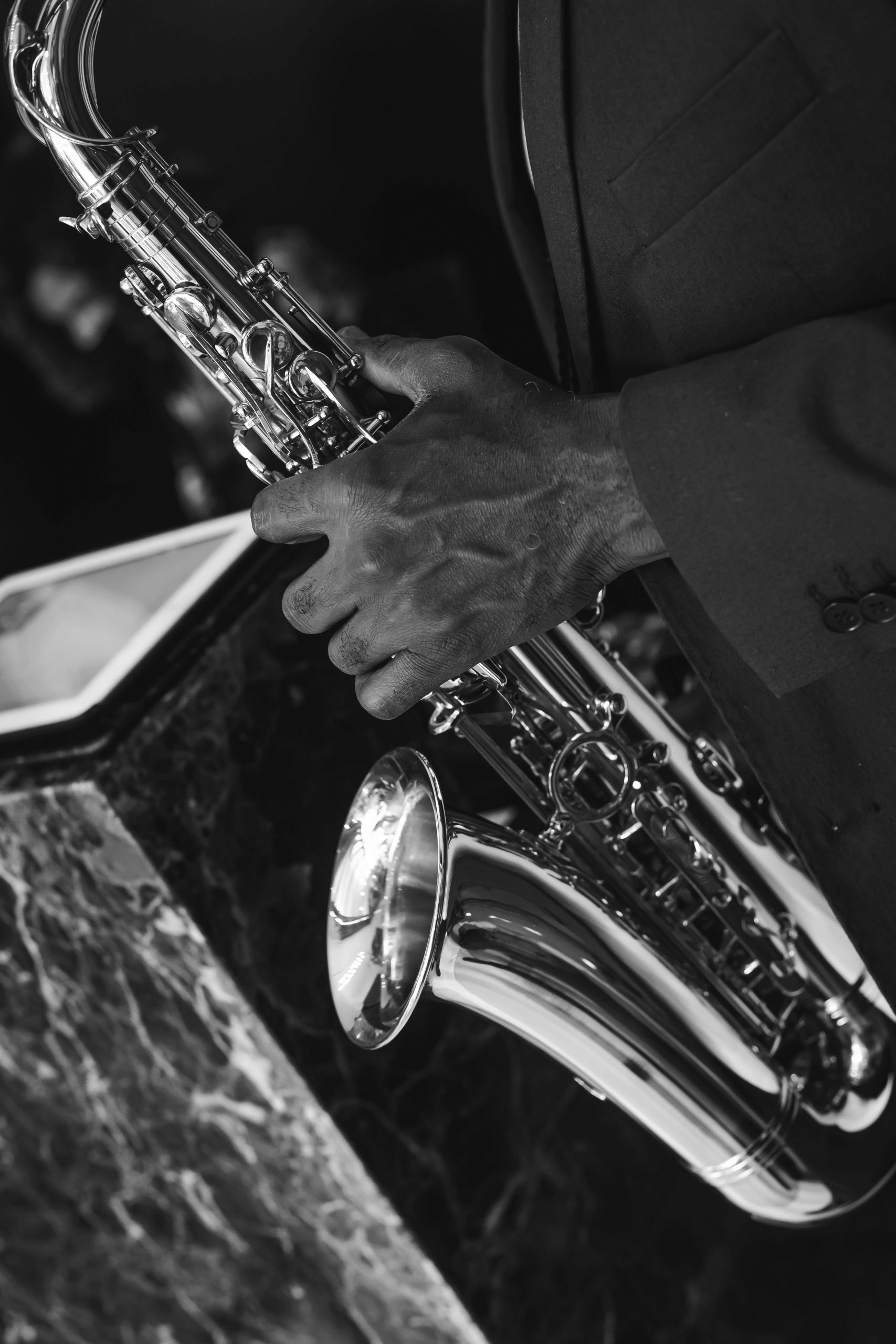 Close-up black and white image of a musician playing the saxophone.
