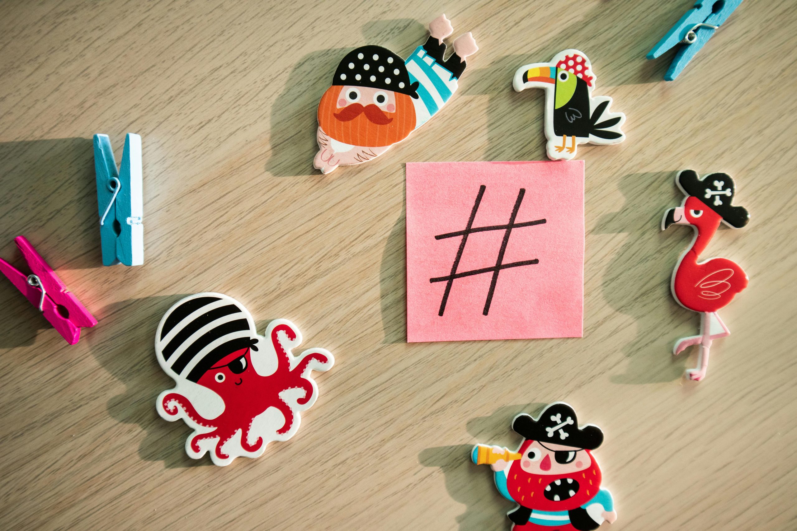Top view of colorful pirate magnets and sticky note on wooden surface.