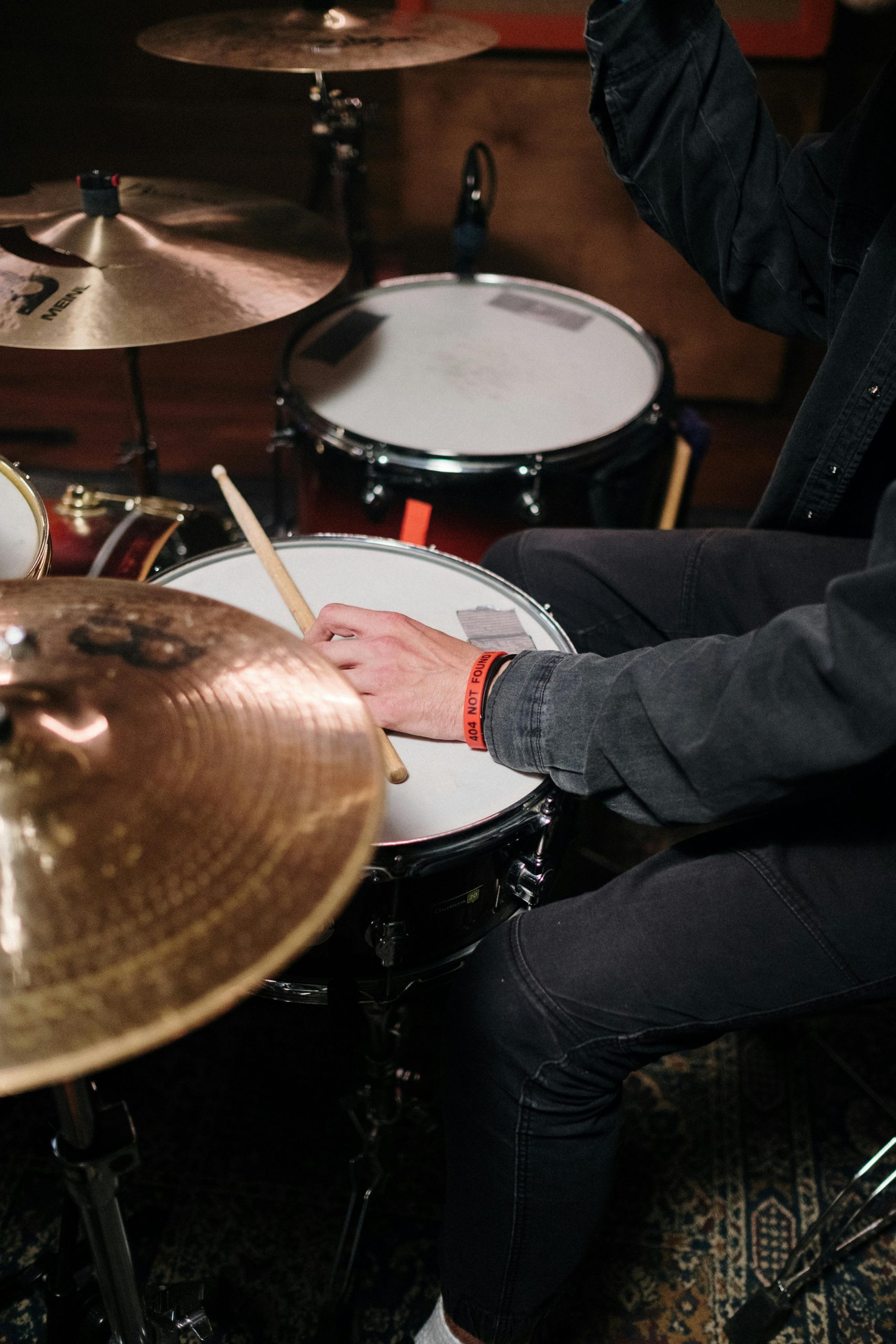 A musician focused on playing a drum set with a close-up view of the cymbals and drumsticks.