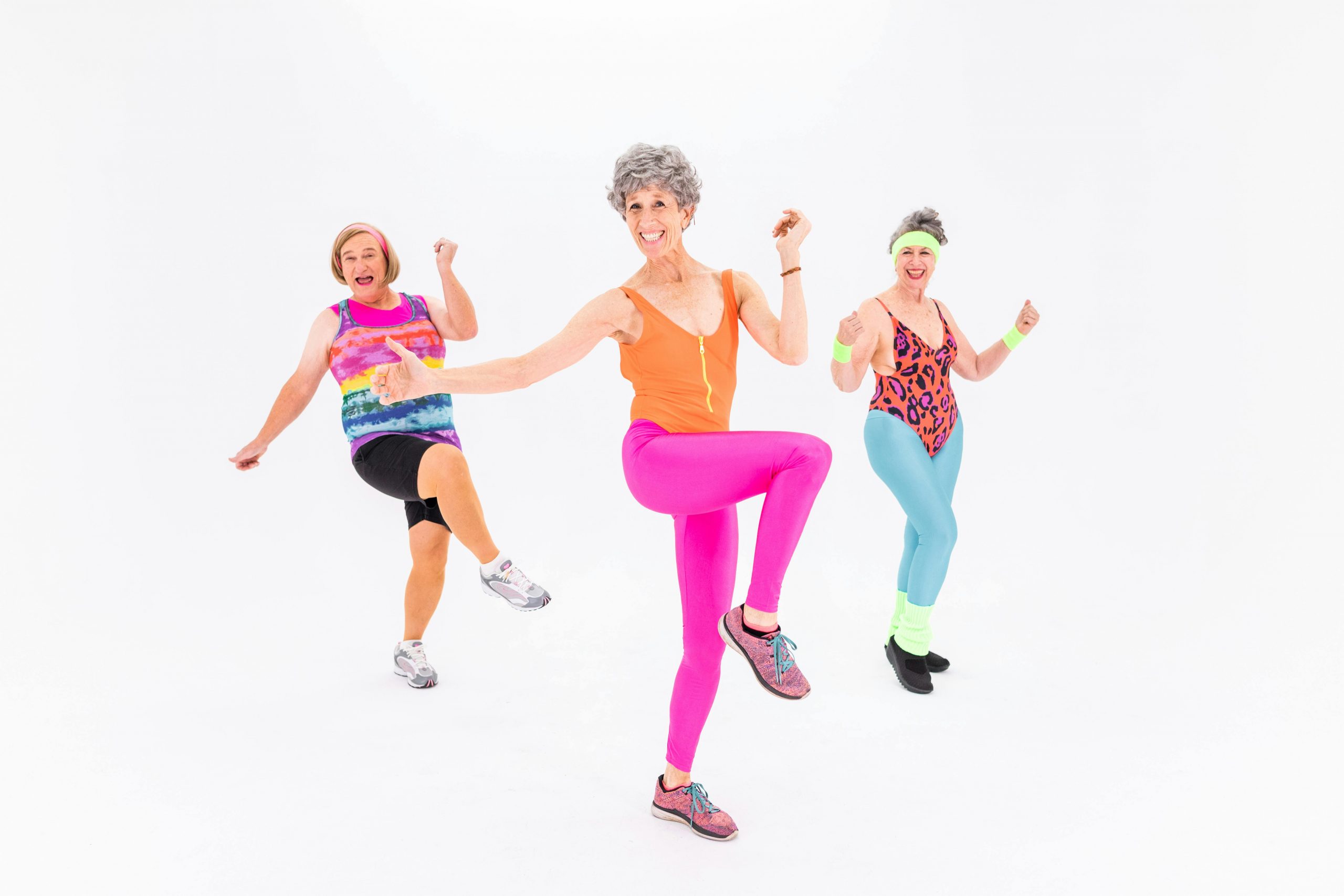 Joyful senior women dancing energetically in colorful activewear, showcasing vibrant senior living and healthy lifestyle.