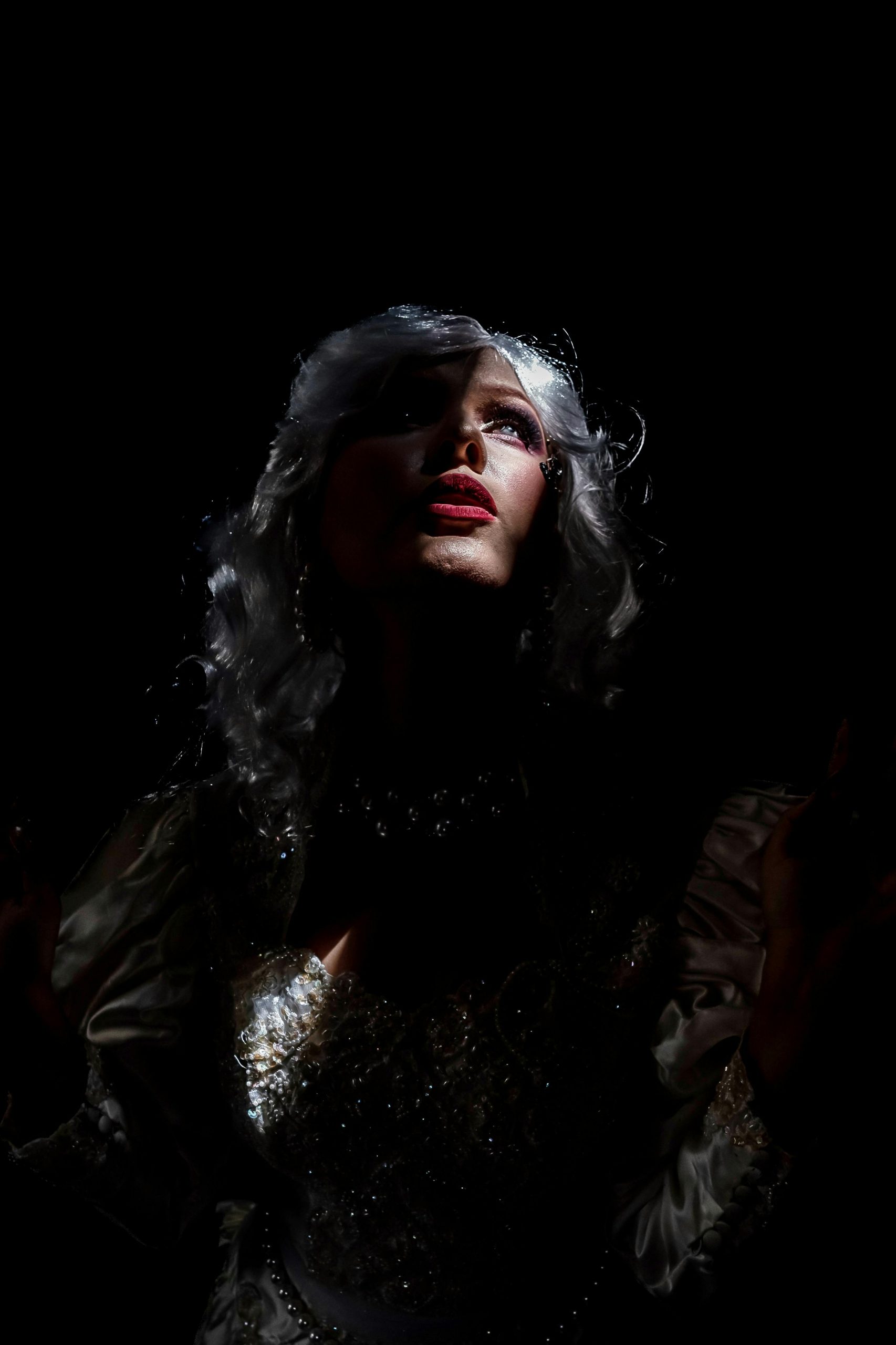 A striking portrait of a woman with dramatic lighting and makeup, conveying mystery and elegance.
