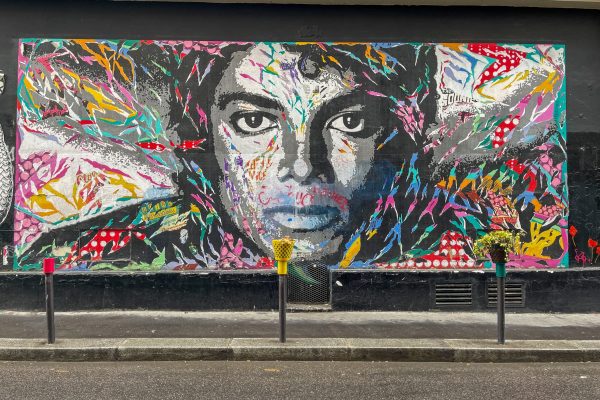 Vibrant mural of a face painted on a wall in Montmartre, Paris, showcasing dynamic street art style.